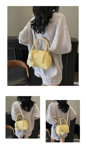 Detail of yellow pillow bag with pearl pendant and embossed text on leather surface