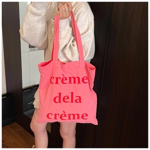 Sac fourre-tout en toile rose avec texte crème dela crème rouge en situation réelle