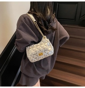 Detailed view of silver quilted chain bag featuring a gold twist lock on woman's shoulder