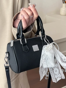 Chic black Boston bag with pearl chain and lace bow charm for a stylish crossbody look