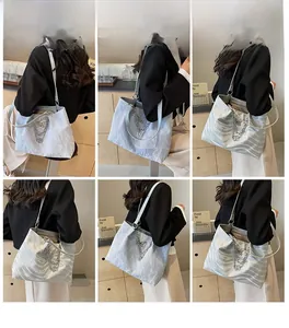 Detail view of the silver tote bag featuring pleated texture and layered metal chains