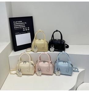 Detail of colorful mini Boston bags with pearl heart pendants and glossy patent finish