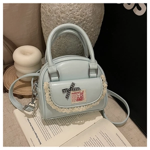 Close-up of light blue mini Boston bag with lace pocket and black-white checkered bow