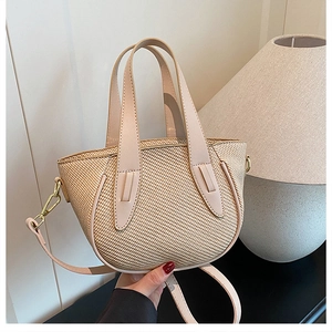 Detailed view of woven straw bucket bag with leather handles and gold metal hardware