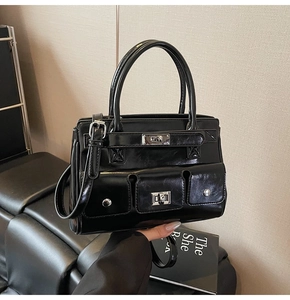 Detailed macro view of the glossy black tote bag with multiple pockets and silver hardware