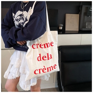 Gros plan sur un sac cabas en toile blanche avec texte rouge crème de la crème imprimé