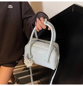 Detail of light blue leather satchel bag with a pearl heart charm and shoulder strap