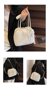 Detail of off-white leather pillow bag with elegant lace bow and pearl pendant
