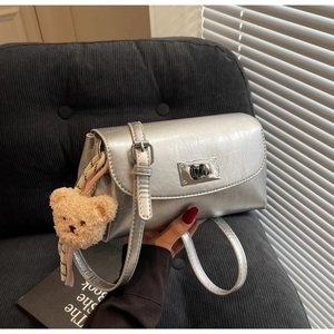 Detail of silver pleated leather bag with square metal lock and teddy bear charm
