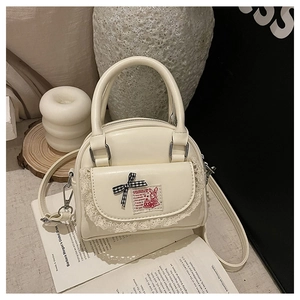 Detail of cream mini Boston bag featuring lace pocket, plaid bow and rabbit patch detail