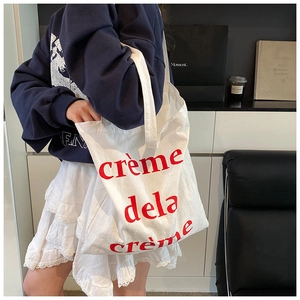 Sac fourre-tout en toile blanche de style français avec lettrage rouge porté à l'épaule