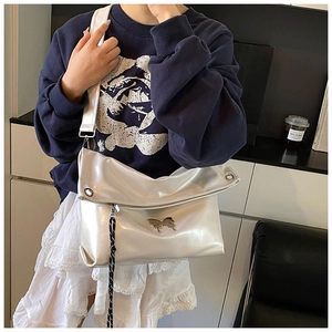 Détail du sac cabas en cuir laser argenté avec papillon métallique et lanière tressée