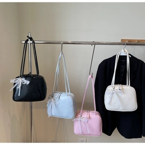 Detail of four colorful Boston bags with pearl lace bows on minimalist hangers