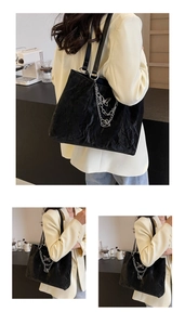 Detail of black tote bag featuring wave pleats, silver chain, and butterfly charm