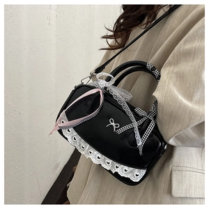 Detail of black glossy Boston bag with white lace trim and pink ribbon decoration
