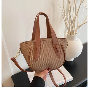 Detailed macro view showing the brown woven texture and vegan leather handle of bucket bag