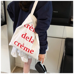 Détail du sac cabas en toile blanche avec texte rouge pour un style décontracté chic