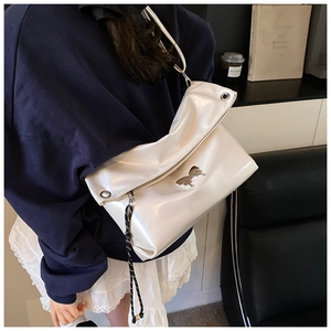 Détail de l'ornement papillon argenté et de la breloque en corde sur un sac fourre-tout blanc