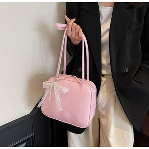 Close-up of pink PU leather underarm bag with white lace bow and pearl pendant detail