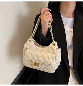 Close-up of beige quilted chain bag with gold twist lock on a fashion model