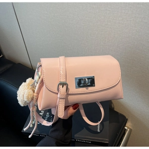 Macro view of pink faux leather pillow bag featuring metallic lock and plush ball charm
