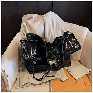 Détail du sac cabas en cuir noir brillant avec œillets argentés et corde tressée