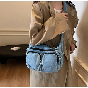 Detailed view of light blue denim tote bag with zipper pockets and frayed edge detailing