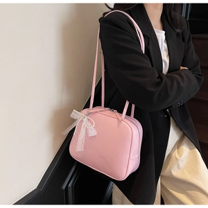 Pink minimalist pillow bag with lace bow and pearl charm detail shown on model