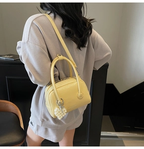 Detail of light yellow leather handbag with pearl heart charm on a gray plaid outfit