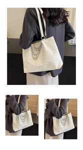 Detail of cream tote bag featuring wave texture and a silver butterfly chain pendant charm