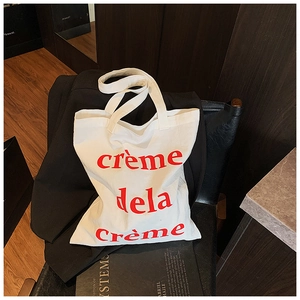 Détail d'un sac cabas en toile blanche avec texte rouge sur une veste de costume noire
