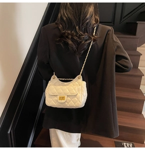 Detail of white quilted handbag with cat-ear silhouette and gold chain on model