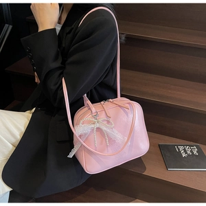 Pink faux leather underarm bag with pearl bow and lace details worn by model