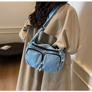 Detail view of washed denim crossbody bag featuring three-zipper pockets and retro style