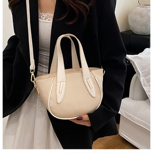 Detail of woven cream bucket bag with leather handles shown in a lifestyle model styling
