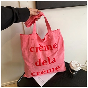 Détail du sac cabas en toile rose avec texte rouge crème de la crème pour usage quotidien