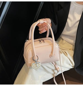 Detail view of pink leather Boston bag with pearl heart charm and metal zippers