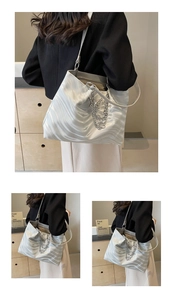 Detail of silver wavy tote bag with metallic butterfly chain and sleek satin texture