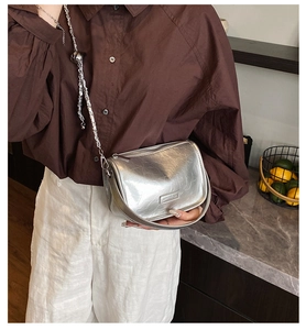 Detail of silver metallic pillow bag with pleated texture and stylish chain strap