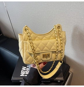 Macro view of pale yellow quilted underarm bag featuring gold turn-lock and chain strap