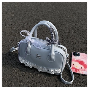 Detailed macro view of the light blue Boston bag with white lace trim and metal bow charm
