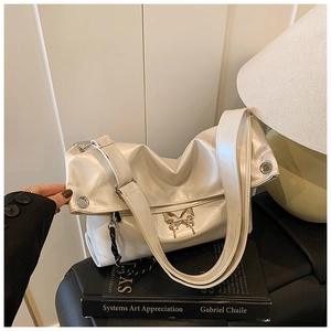 Détail du sac cabas blanc brillant perlé avec breloque papillon et chaîne tressée
