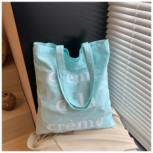 Détail du sac cabas bleu clair avec texte Creme dela Creme blanc et texture de la toile