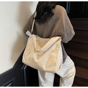 Detail of beige quilted tote bag with a lace bow on a shoulder strap in use