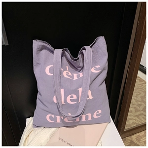 Vue détaillée du sac cabas en toile violette avec texte rose Crème de la Crème