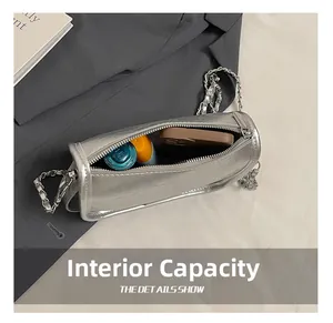 Macro detail showing spacious interior of a silver cylinder bag with metal chain