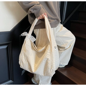 Detail of off-white tote bag with textured fabric and delicate lace bow on the side