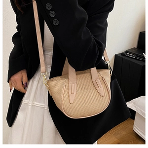 Close-up of beige woven bucket bag featuring pink leather handle and gold hardware detail