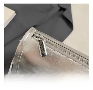 Close-up of high-polish silver metal zipper on a metallic textured cylinder pillow bag