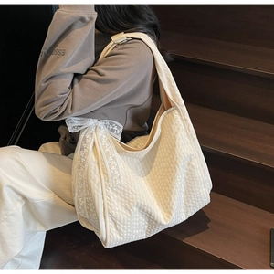Detail of off-white hobo bag with small grid texture and a delicate white lace bow